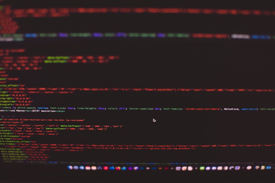 Close-up of a computer screen displaying colorful lines of code on a dark background, with various sections highlighted in red, green, and purple. The screen appears blurred, but the structure of the 